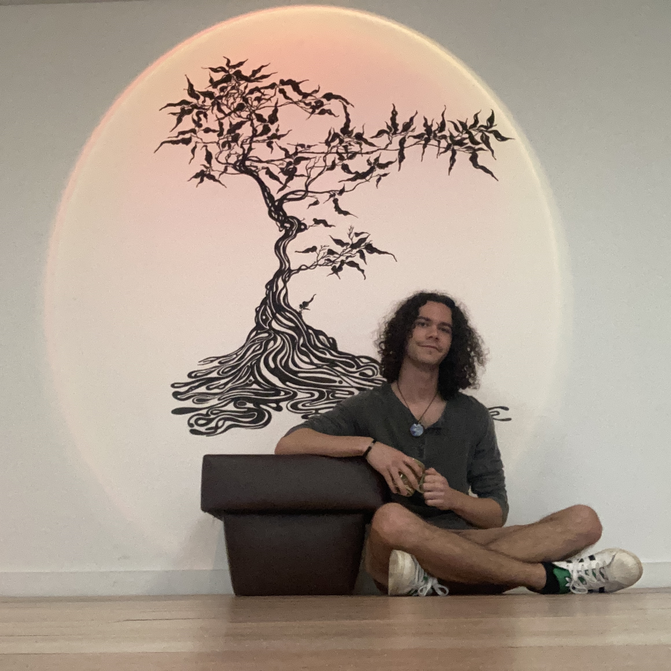Jordan Sbrana seated in the counselling space beside a tree mural
